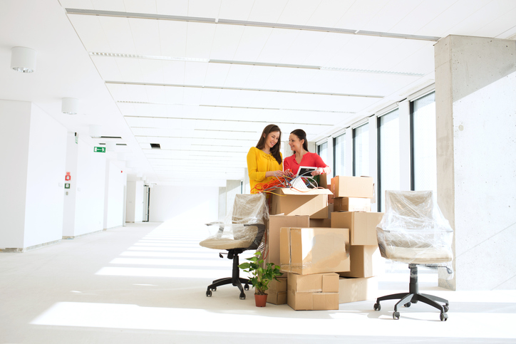 two women unpacking boxes in new office